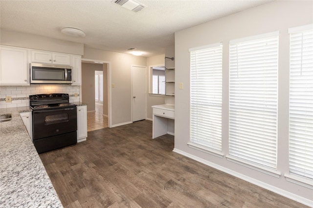 kitchen featuring visible vents, dark wood-type flooring, black range with electric stovetop, stainless steel microwave, and tasteful backsplash