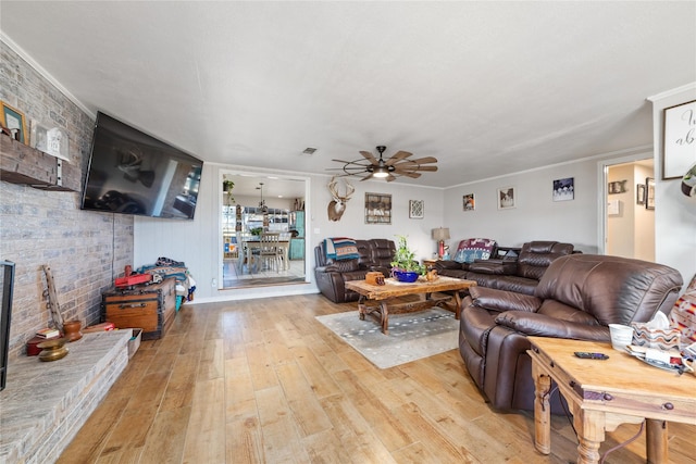 living area featuring light wood-type flooring, visible vents, and ceiling fan