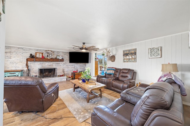 living area featuring a fireplace, wood finished floors, brick wall, and a ceiling fan