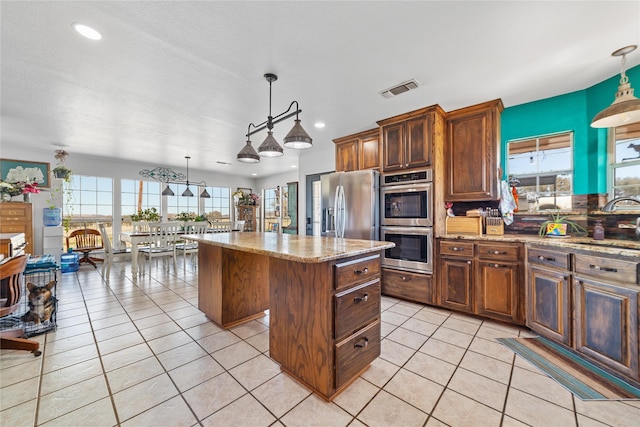 kitchen featuring light tile patterned floors, stainless steel appliances, visible vents, and a center island