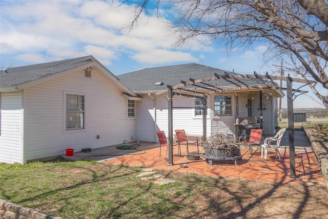 rear view of house with a patio, a pergola, a shingled roof, a fire pit, and a lawn