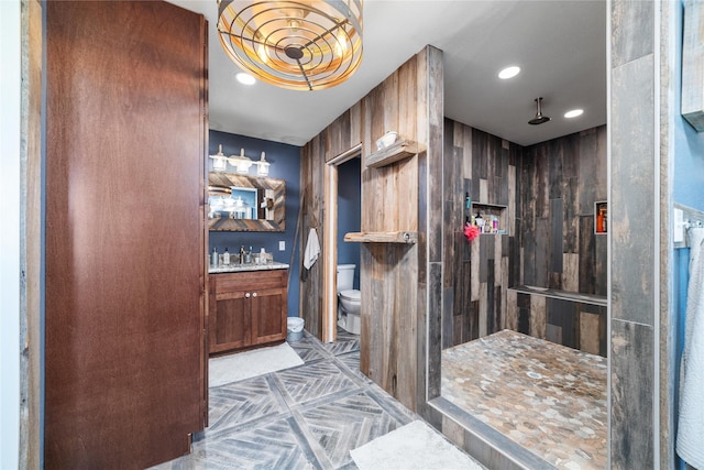 interior space with vanity, toilet, recessed lighting, and tiled shower