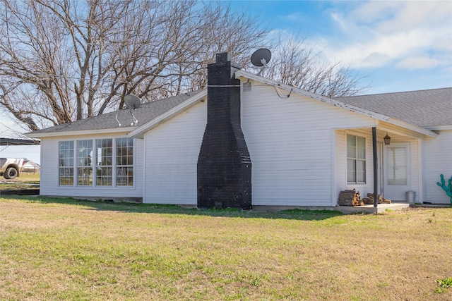 view of side of home with a yard, a chimney, and a shingled roof