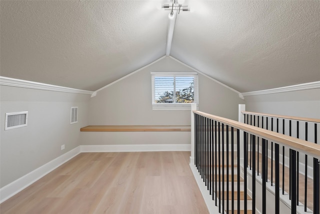 bonus room featuring lofted ceiling, wood finished floors, visible vents, and a textured ceiling