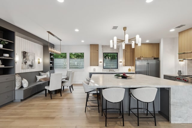 kitchen with visible vents, modern cabinets, premium appliances, a kitchen island, and a chandelier