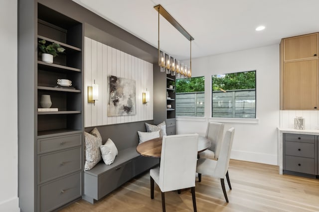 dining space with built in shelves, light wood-style floors, baseboards, and breakfast area