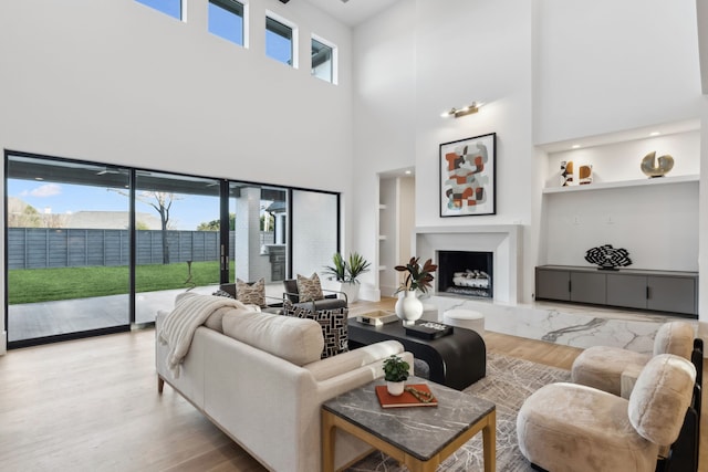 living room with a premium fireplace, built in features, and wood finished floors