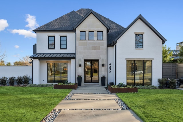 view of front of property featuring a standing seam roof, a front lawn, brick siding, and metal roof