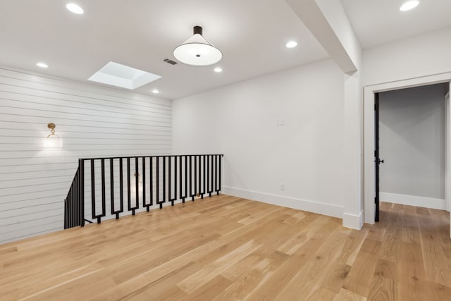 empty room featuring visible vents, baseboards, recessed lighting, a skylight, and wood finished floors