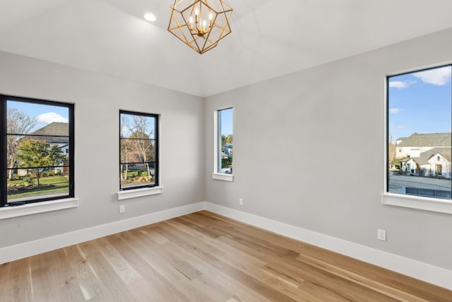 unfurnished room featuring an inviting chandelier, baseboards, and light wood-type flooring