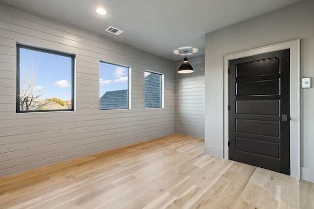 spare room featuring wooden walls, recessed lighting, wood finished floors, and visible vents