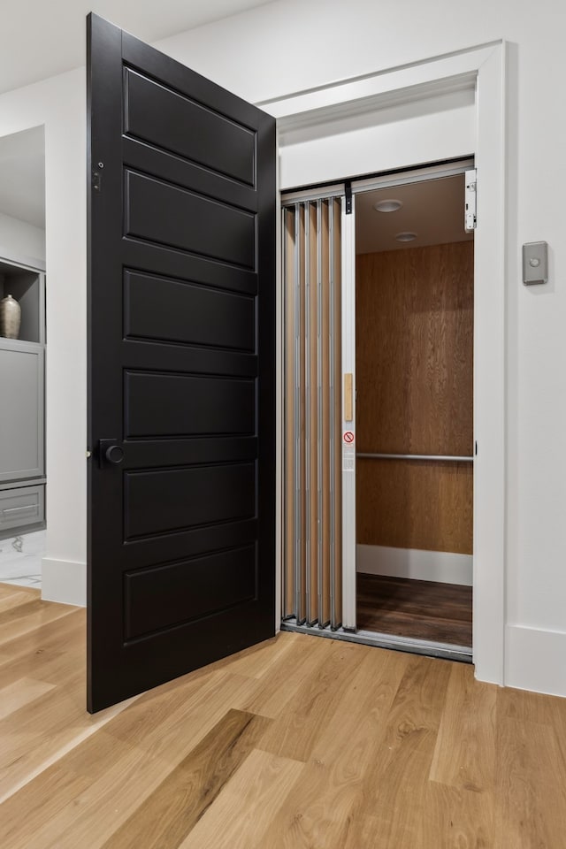 hallway featuring baseboards and light wood-style floors