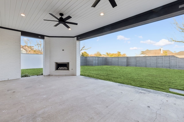 view of patio / terrace featuring a ceiling fan, a fenced backyard, and a large fireplace