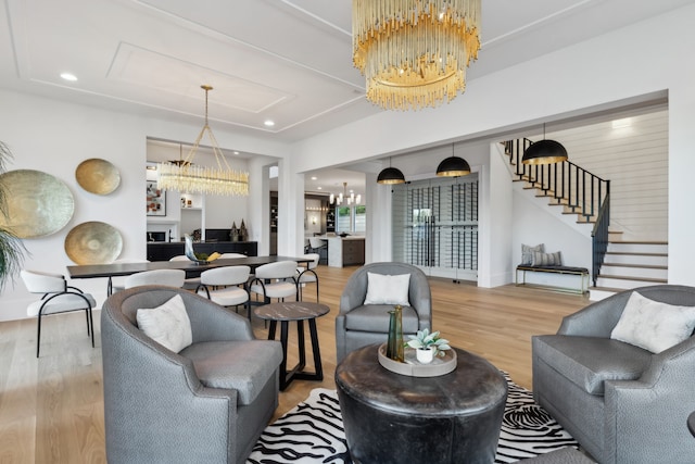 living area with stairway, recessed lighting, a fireplace, wood finished floors, and a notable chandelier