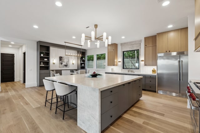 kitchen featuring a spacious island, premium appliances, gray cabinets, and light wood finished floors