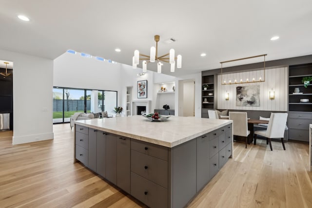 kitchen with a spacious island, open floor plan, gray cabinets, and light wood-type flooring