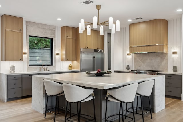 kitchen featuring light wood-style floors, tasteful backsplash, a kitchen island, and stainless steel built in refrigerator