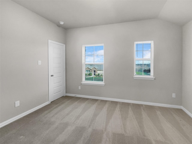 spare room featuring light carpet, plenty of natural light, and lofted ceiling