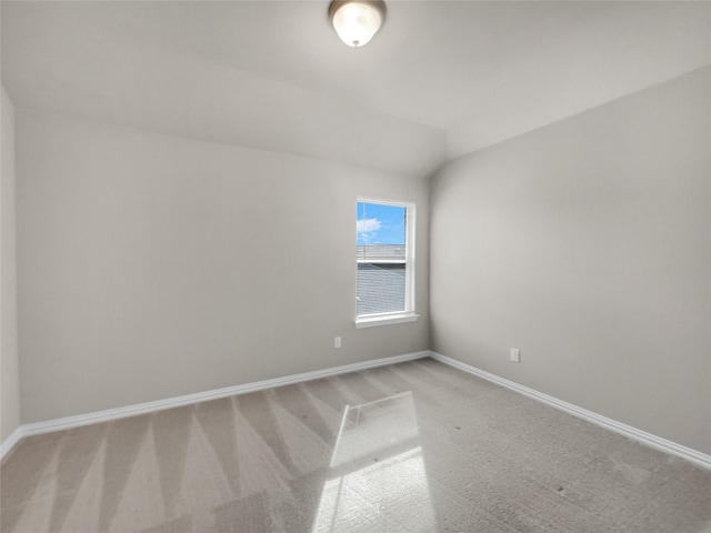 carpeted spare room with baseboards and vaulted ceiling