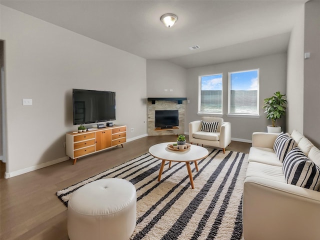 living area with visible vents, baseboards, a fireplace, and vaulted ceiling