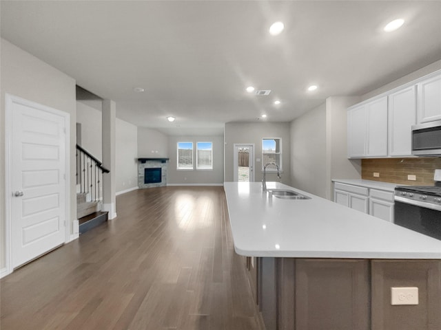 kitchen with a sink, stainless steel microwave, tasteful backsplash, light countertops, and range