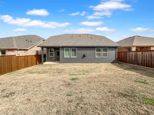 rear view of house with a lawn, a patio, a fenced backyard, and roof with shingles