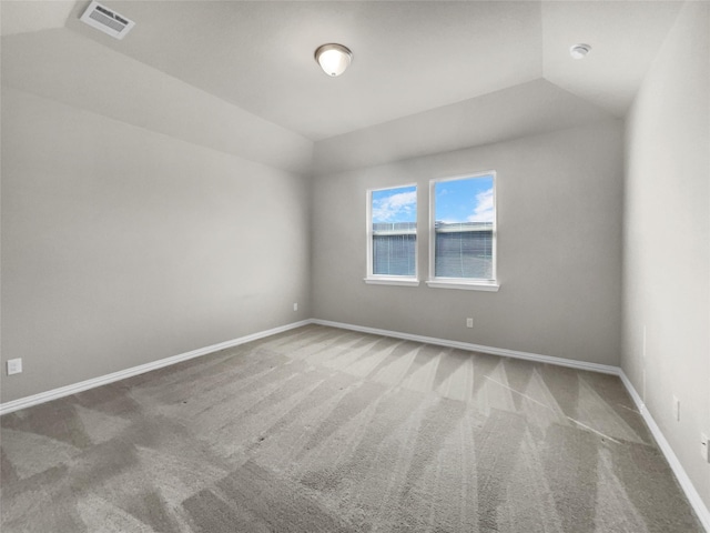 spare room featuring visible vents, baseboards, carpet flooring, and vaulted ceiling