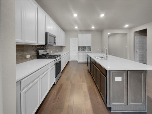 kitchen with a sink, stainless steel appliances, wood finished floors, and light countertops