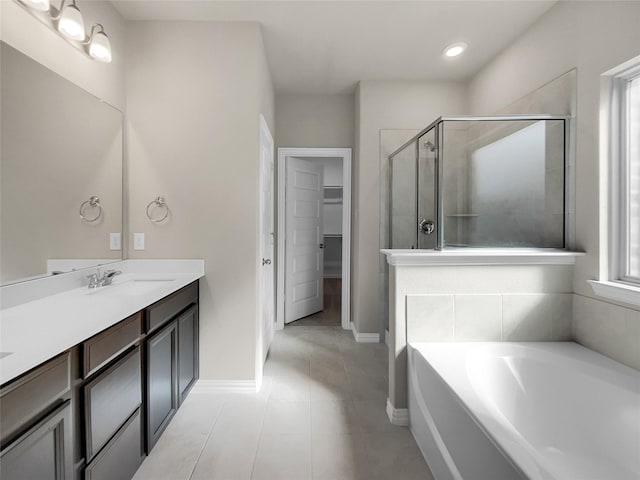 full bath featuring tile patterned floors, a garden tub, a shower stall, a spacious closet, and vanity