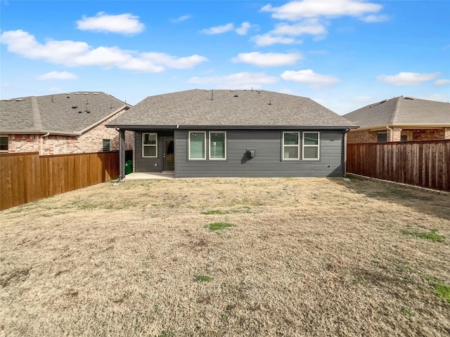 back of house with a yard, a shingled roof, and a fenced backyard