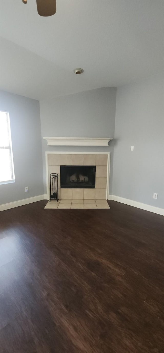 unfurnished living room with baseboards, wood finished floors, and a tiled fireplace