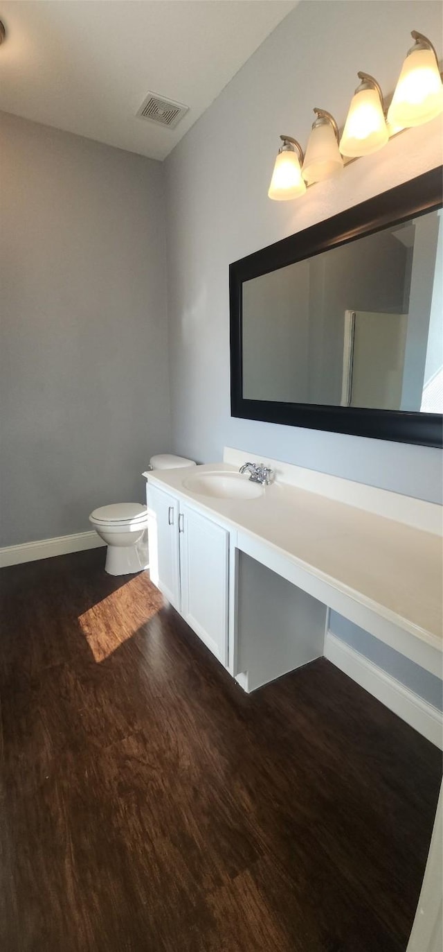 bathroom featuring vanity, wood finished floors, visible vents, baseboards, and toilet