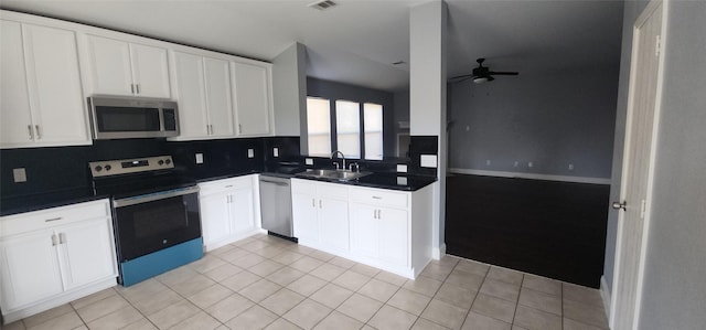 kitchen featuring a sink, dark countertops, backsplash, stainless steel appliances, and ceiling fan