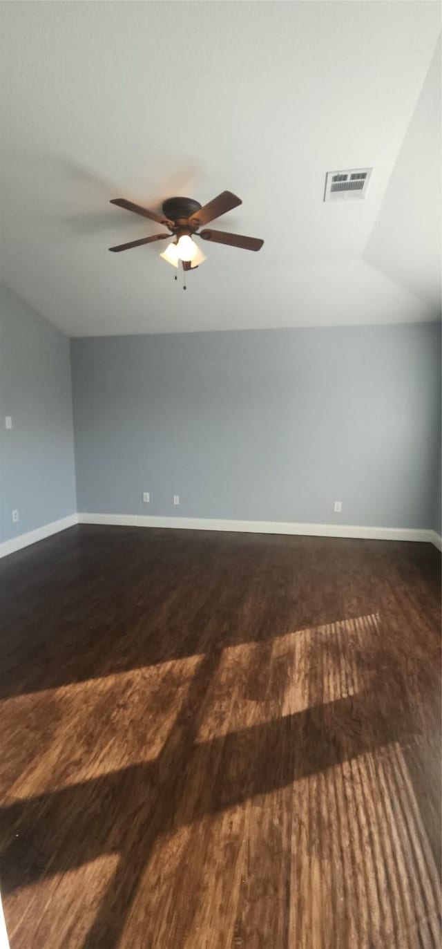 unfurnished room featuring visible vents, baseboards, lofted ceiling, and dark wood-style flooring