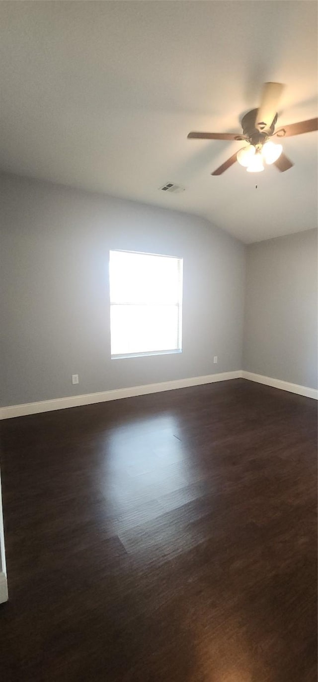 unfurnished room with baseboards, visible vents, dark wood-style flooring, ceiling fan, and vaulted ceiling