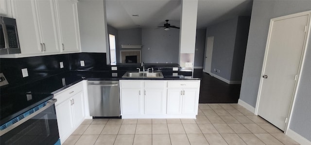 kitchen with a ceiling fan, a sink, stainless steel appliances, white cabinets, and dark countertops