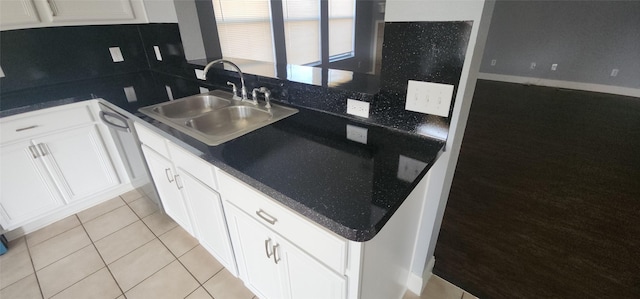 kitchen with light tile patterned floors, a sink, white cabinets, dark countertops, and backsplash