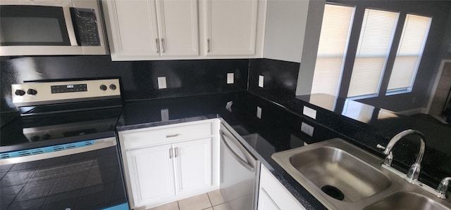 kitchen featuring a sink, stainless steel appliances, dark countertops, and white cabinetry