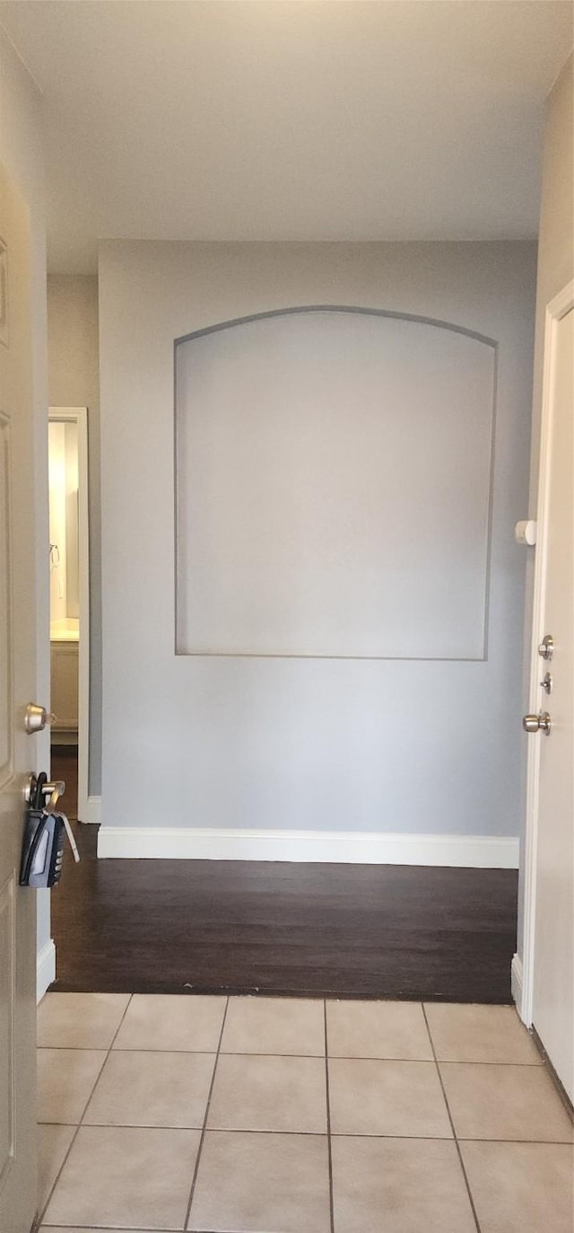 hall featuring baseboards and light tile patterned flooring