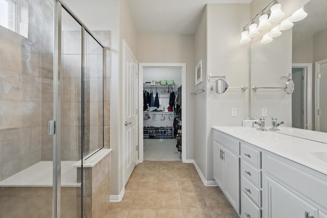 full bathroom with tile patterned floors, a shower stall, a walk in closet, and double vanity