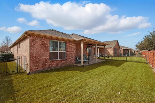 back of house featuring roof with shingles, a yard, a fenced backyard, a patio area, and brick siding