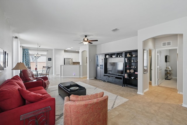 living area with arched walkways, visible vents, ceiling fan with notable chandelier, and baseboards