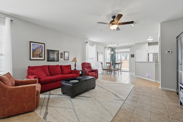 living area with light tile patterned flooring, baseboards, and ceiling fan