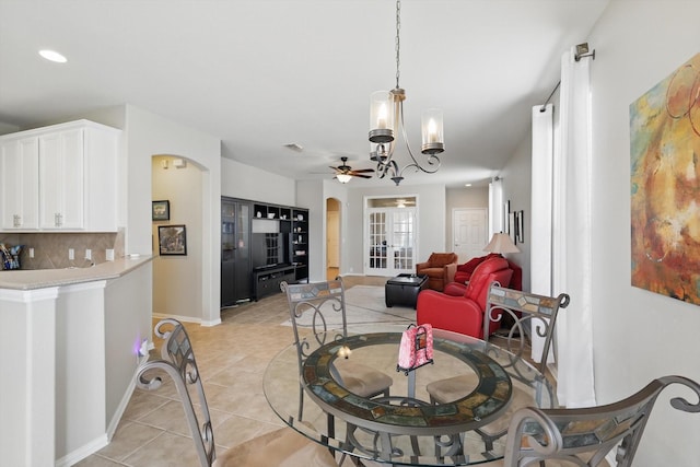 dining space featuring baseboards, light tile patterned flooring, recessed lighting, arched walkways, and ceiling fan with notable chandelier