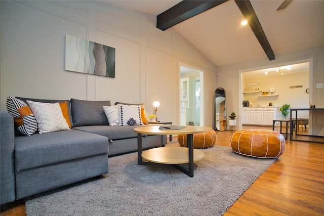 living area with vaulted ceiling with beams and wood finished floors