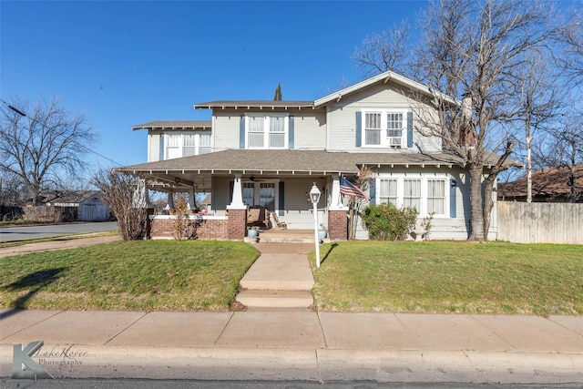 view of front of house with brick siding, covered porch, a front yard, and fence