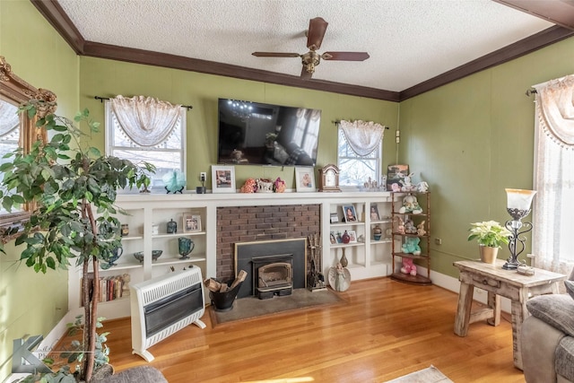 living area featuring heating unit, a textured ceiling, crown molding, and wood finished floors