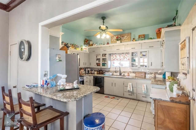 kitchen featuring a sink, freestanding refrigerator, a peninsula, light tile patterned floors, and dishwasher