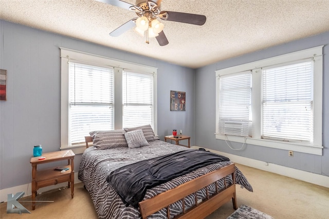 carpeted bedroom with multiple windows, a textured ceiling, and a ceiling fan