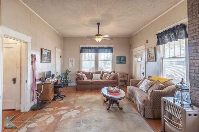 living area featuring ceiling fan, a textured ceiling, wood finished floors, and crown molding